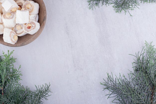 Serving of turkish delights and pine branches on white background.