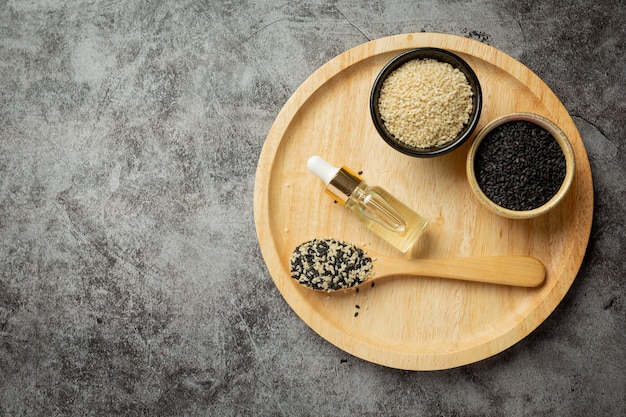 Sesame oil and sesame seeds on dark background