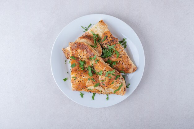 Sesame pita with chopped parsley on plate, on the marble.