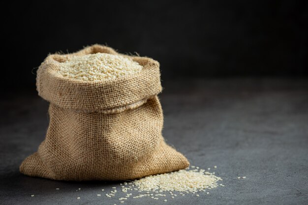 Sesame seeds in bag on dark background