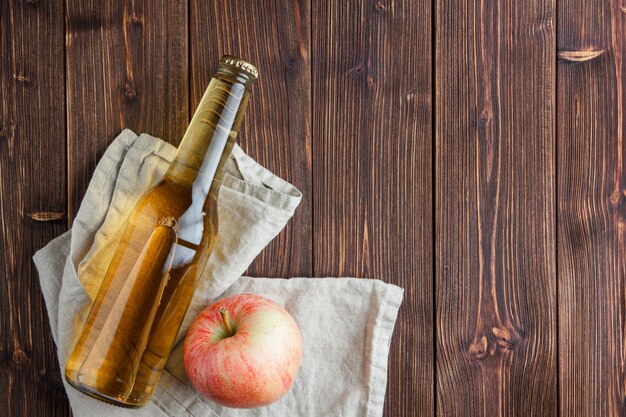 Комплект яблочного сока и яблока на ткани и деревянной предпосылке. вид сверху. место для текста