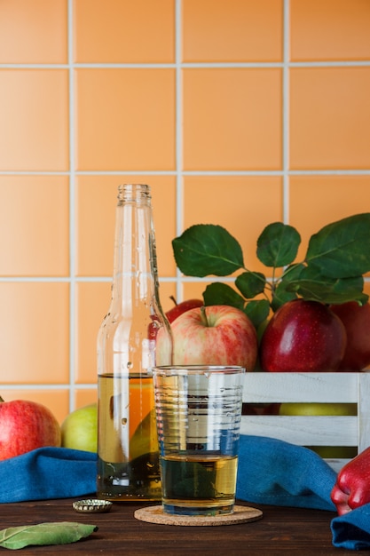 Insieme del succo e delle mele di mele in una scatola su un fondo di legno ed arancio delle mattonelle. vista laterale. spazio per il testo