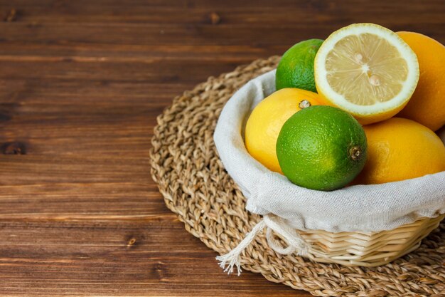 Набор корзины с лимоном и половиной лимона и лимона на деревянной поверхности. высокий угол обзора.
