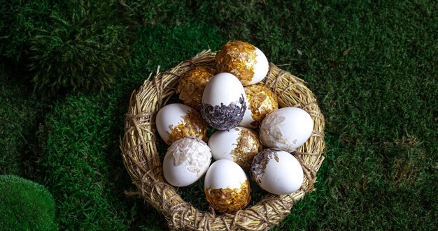 Набор красивых пасхальных яиц в декоративном гнезде на мхе