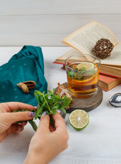 Set of books, lemon, mint and green scarf and herbal tea and cinnamon on a wooden board