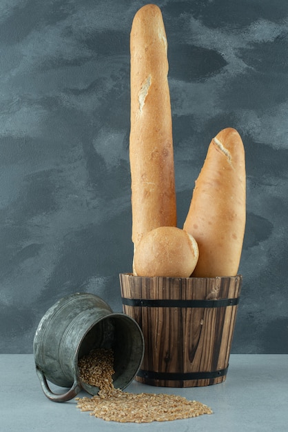 Set of bread in bucket with mug of barley on stone surface