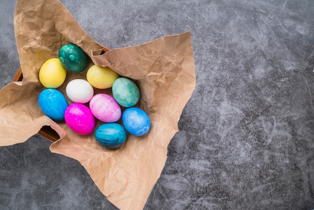 Set of bright Easter eggs on craft paper in bowl