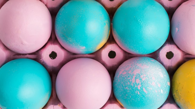 Set of bright Easter eggs in pink container