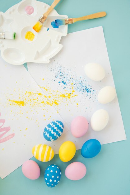 Set of bright eggs near sheets and brushes