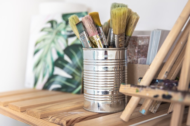 A set of brushes for painting in a tin can on a shelf in the workshop