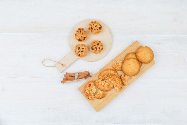 Set of cinnamon and different cookies on a cutting boards on a white surface