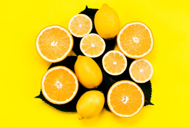 Set of citrus fruits on leaves on yellow background