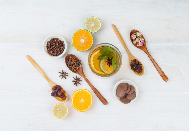 Set of citrus fruits, pancakes, cloves, dried fruits and rosebuds and fermented drink on a white surface