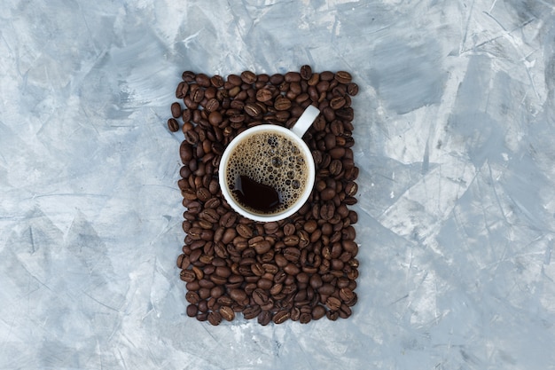 Set of coffee beans and coffee in a cup on a blue marble background. top view.