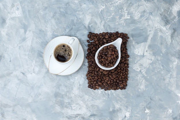 파란 대리석 배경에 흰색 도자기 용기에 커피와 커피 콩의 컵의 집합입니다. 평면도.