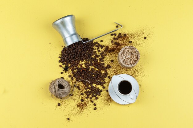 黄色の背景の水差しにコーヒー、お餅、ロープ、コーヒー豆のセット。フラットレイ。
