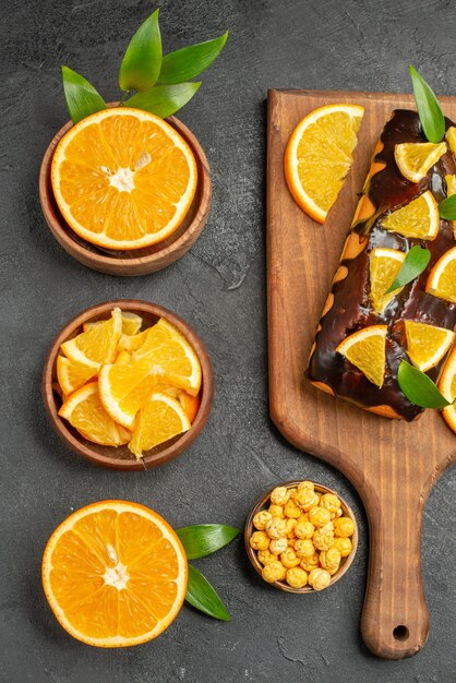 Foto gratuita set di taglio a metà affettato su pezzi di arance fresche e torte morbide sulla tavola nera