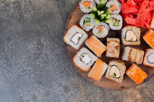 Set of delicious different sushi on wooden plate