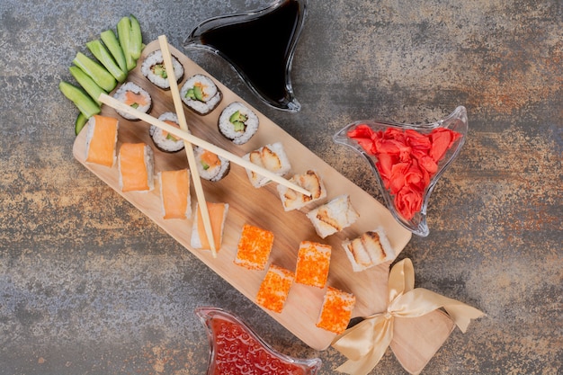 Набор вкусных суши с палочками для еды и имбирем на мраморной поверхности