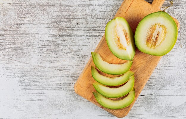 Set of divided in half melon on cutting board and sliced melon on a white stone background. top view. space for text