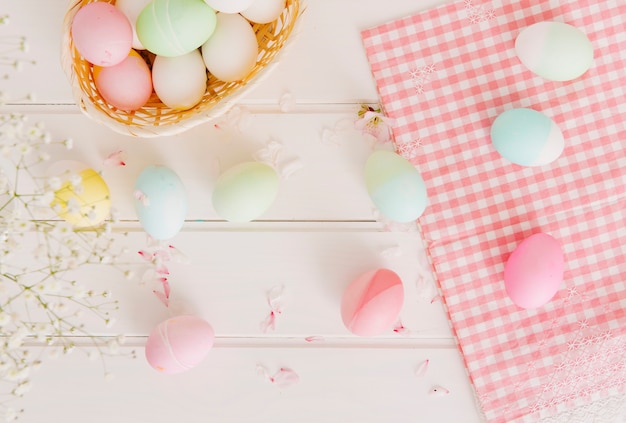 Set of Easter eggs between flower petals near napkin and basket