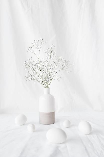 Set of Easter eggs near plant branches in vase