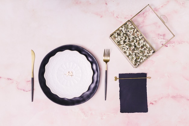 Set of flowers in box and paper near plate and cutlery