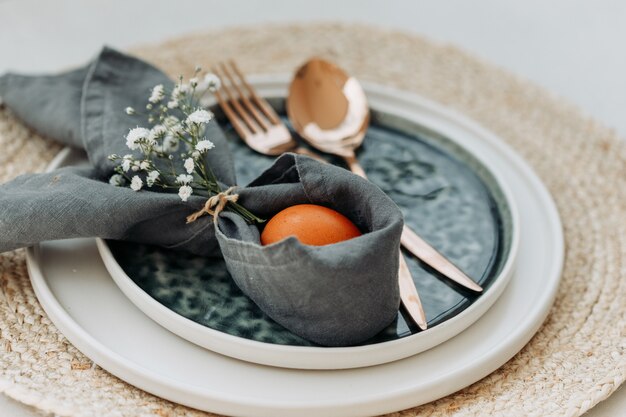 Set of fork and spoon and an egg in a plate with cloth on trivet and white. high angle view.