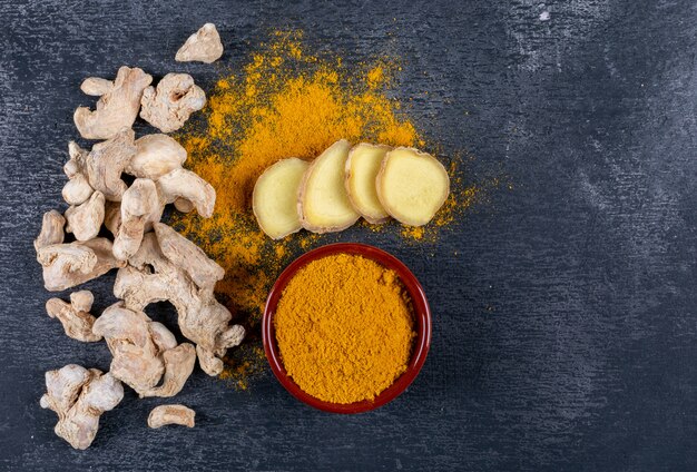 Set of ginger slices and powder and ginger in a bowl on a dark textured background. top view. space for text