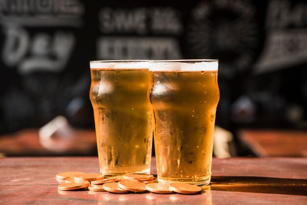 Set of glasses of drink near heap of coins at table