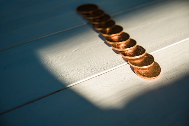 Set of golden coins on board and sunshine in darkness