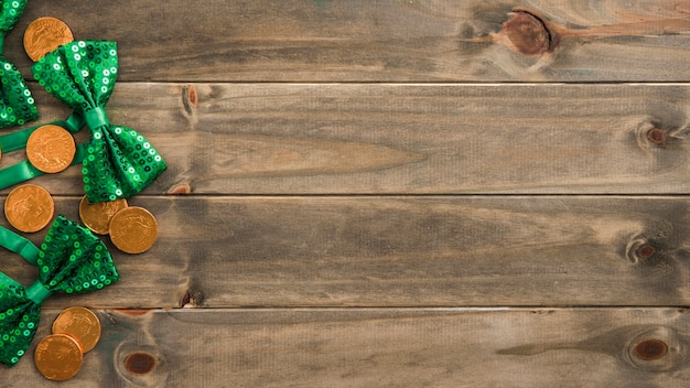 Set of golden coins and bow ties on wooden board