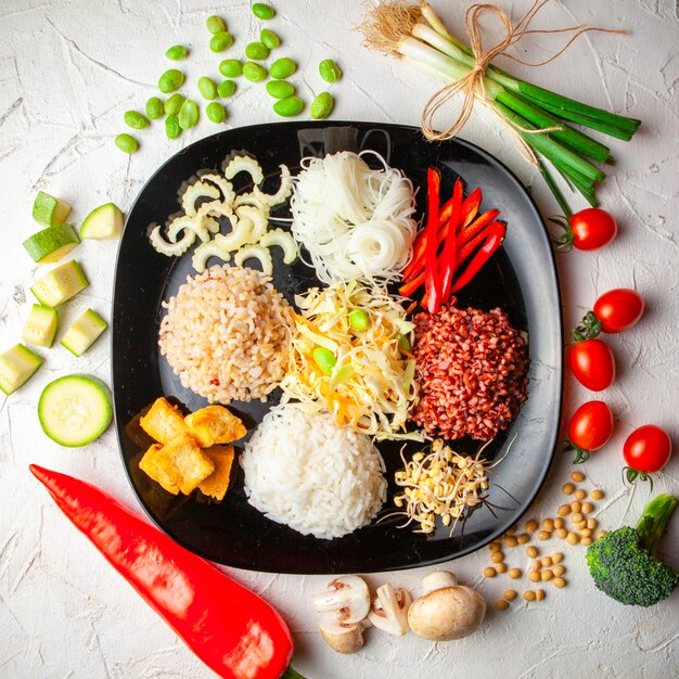 Set of green onion and red pepper and delicious meals in a black plate on a white textured background. top view.