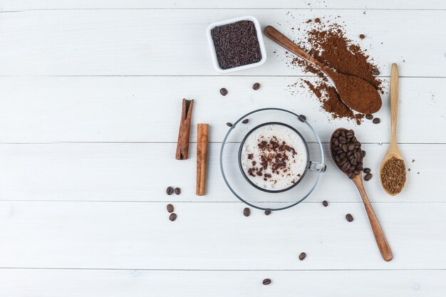 Set of grinded coffee, coffee beans, cinnamon sticks and coffee in a cup on a wooden background. top view.