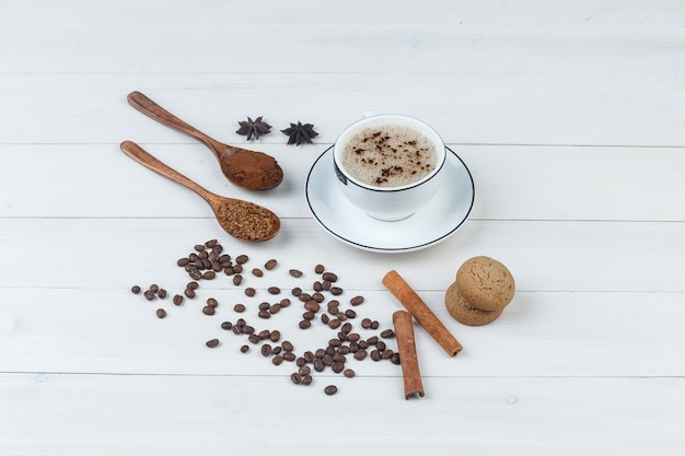 Set of grinded coffee, spices, coffee beans, cookies and coffee in a cup on a wooden background. high angle view.