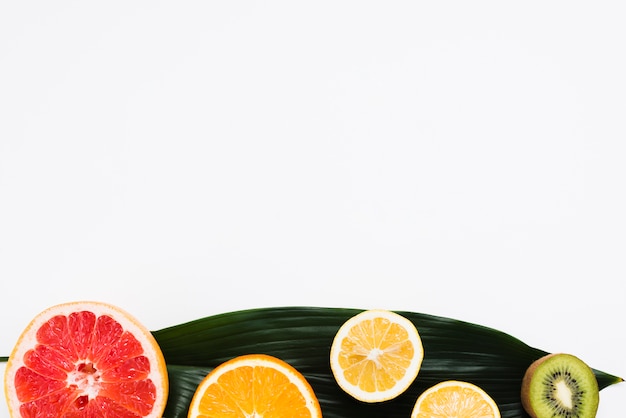 Set of half of tropical fruits on banana leaf on white background