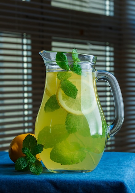 Set of leaves and lemon and carafe of lemon juice on a black window surface. side view.