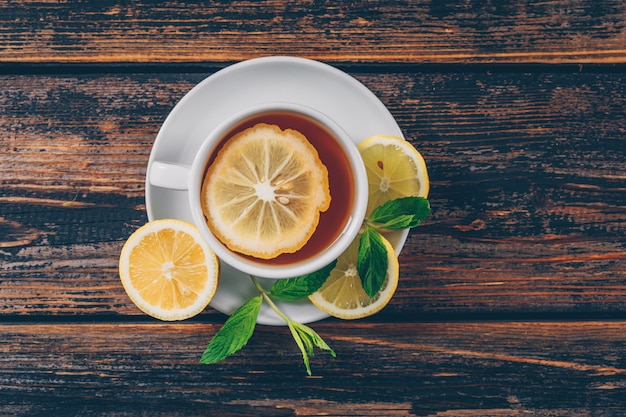 Set of lemon and a cup of tea on a dark wooden background. flat lay. space for text