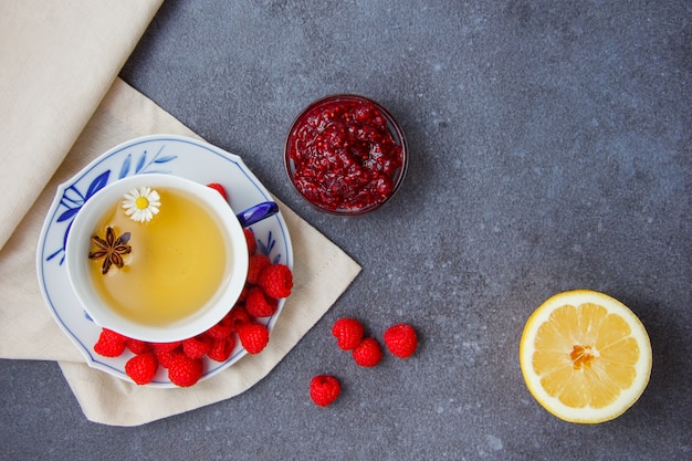 Foto gratuita set di marmellata di limone, lamponi e lamponi in piattini e una tazza di camomilla su un panno