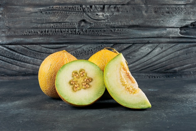 Set of melon and sliced melon on a dark wooden background. side view.