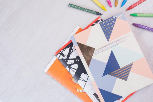 Free photo set of notebooks and colorful pencils on white surface.