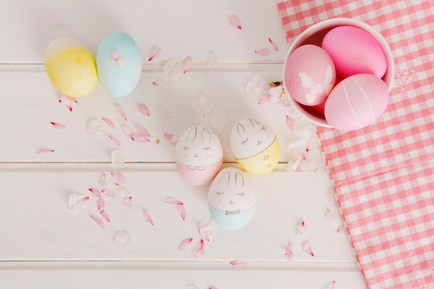 Бесплатное фото Набор пасхальных яиц между лепестками цветов возле салфетки и чаши