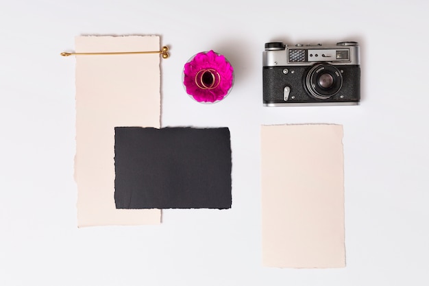 Free photo set of papers near fresh flower with rings on plate and retro camera