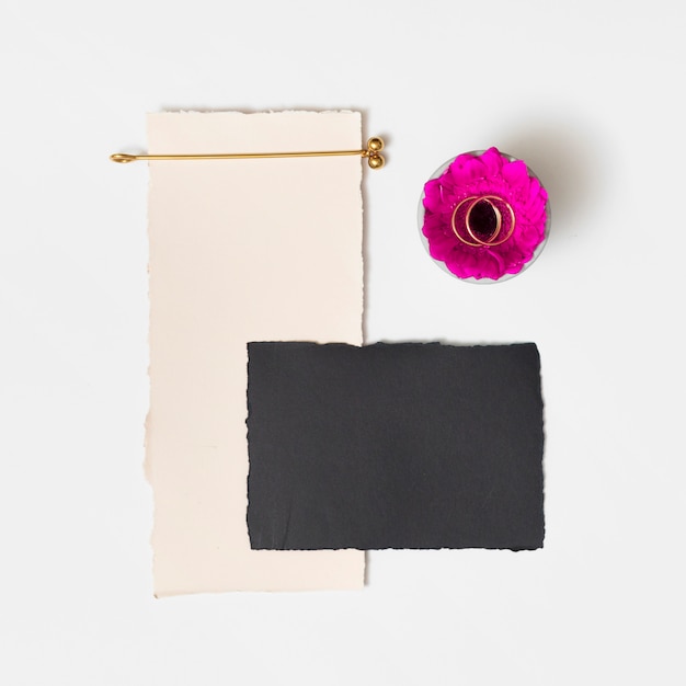 Free photo set of papers near fresh flower with rings on plate