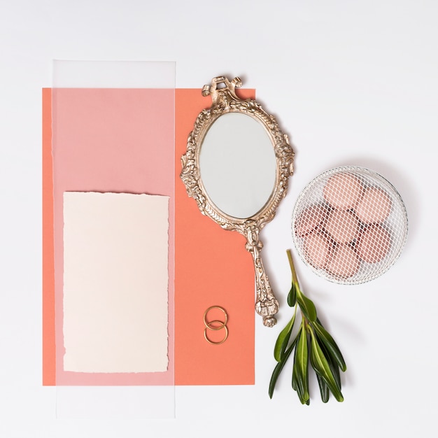 Set of papers near macaroons on plate, rings and mirror