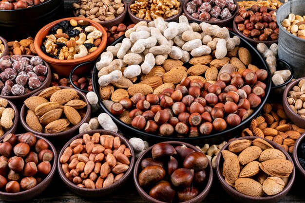 Set of pecan, pistachios, almond, peanut, cashew, pine nuts and assorted nuts and dried fruits in a different bowls . side view.