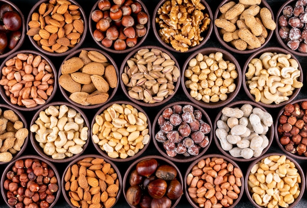 Set of pecan, pistachios, almond, peanut, cashew, pine nuts and lined up assorted nuts and dried fruits in a mini different bowls