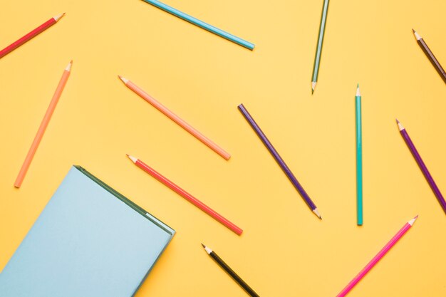 Set of pencils scattered on yellow background