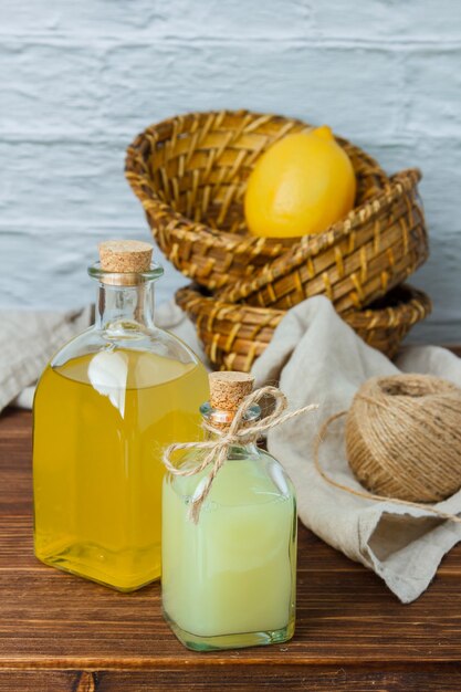 Set of on piece of white cloth, lemon leaves and lemon and juice in a basket on a wooden surface. high angle view. space for text