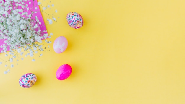 Set of pink Easter eggs near flowers on napkin